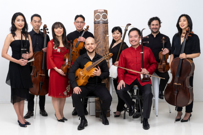 Nine members of INTERWOVEN ensemble poses with instruments